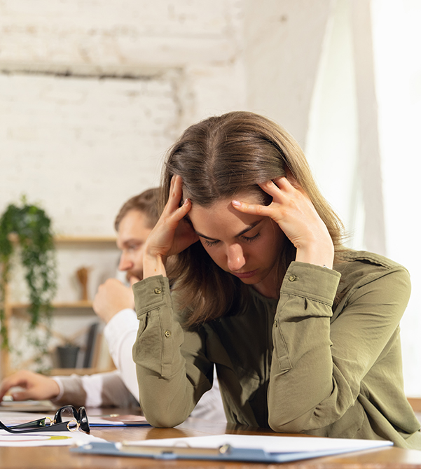 stressed woman sat at desk with head in hands